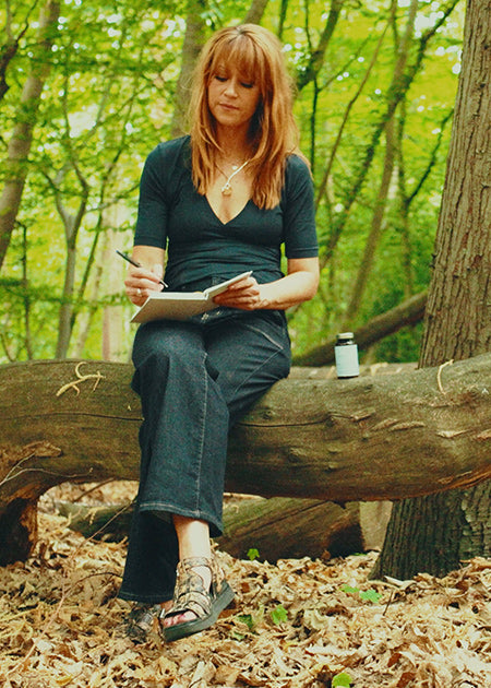 Woman takes Curated Beauty supplement in sunny forest